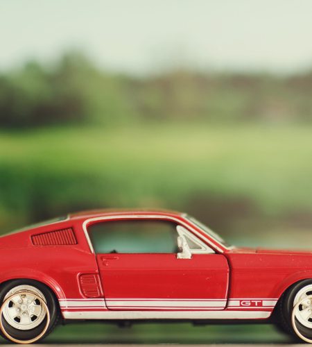 Wedding rings lie behind the wheels of a toy red Mustang